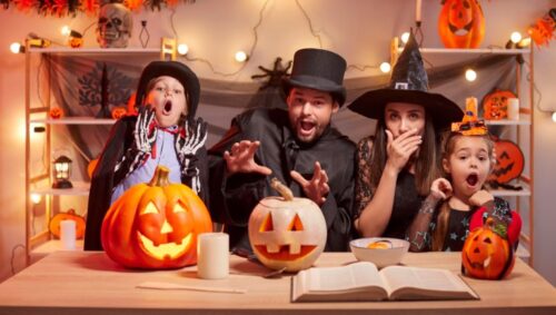 A family trying to look scary on halloween while surrounded by pumpkins, candy, and decorations
