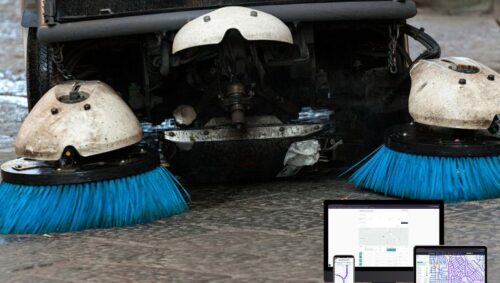 Street sweeper vehicle cleaning a city roadway with digital route tracking and performance analytics overlay.